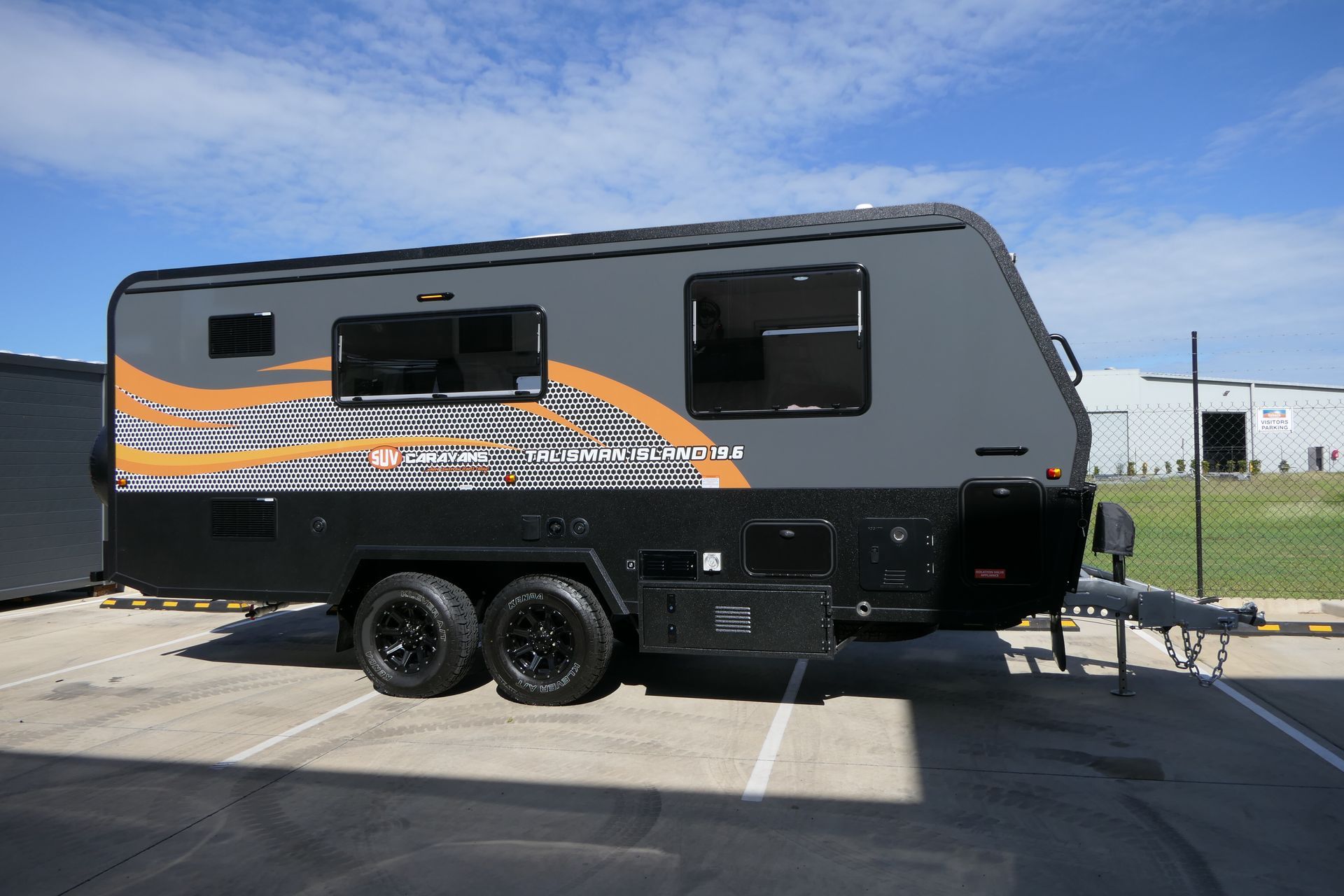 A gray and orange camper trailer is parked in a parking lot.