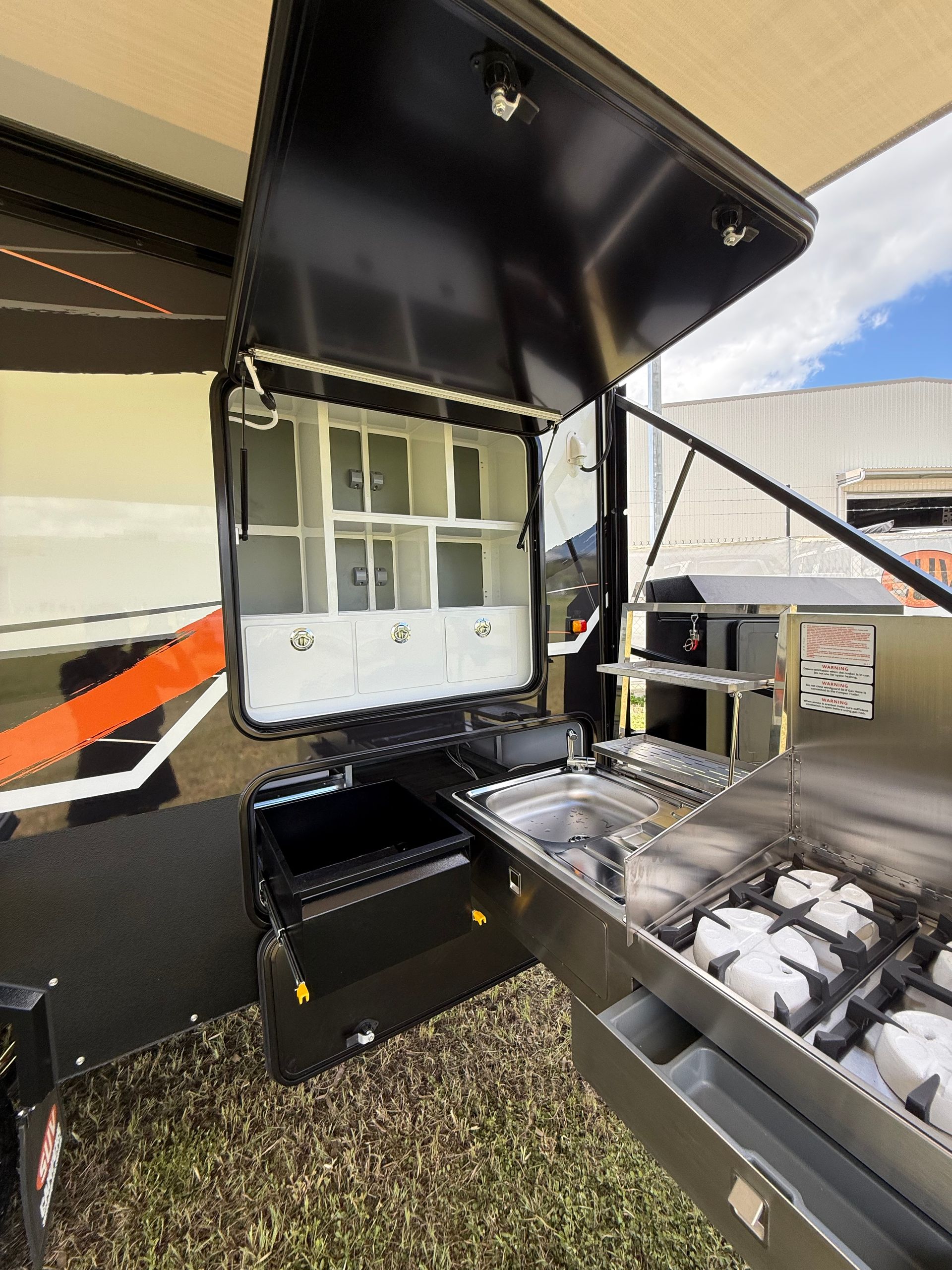 A kitchen with a stove and a sink in a trailer.