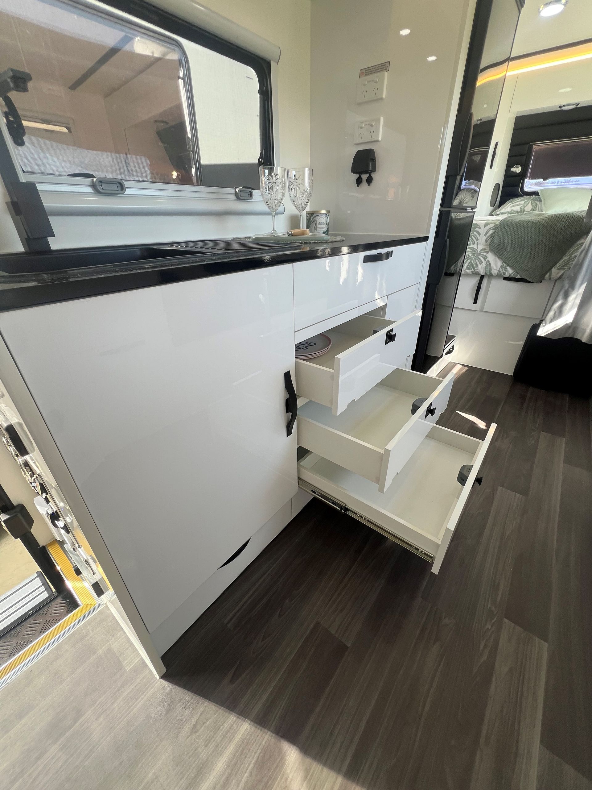 A white cabinet with drawers open in a camper van.