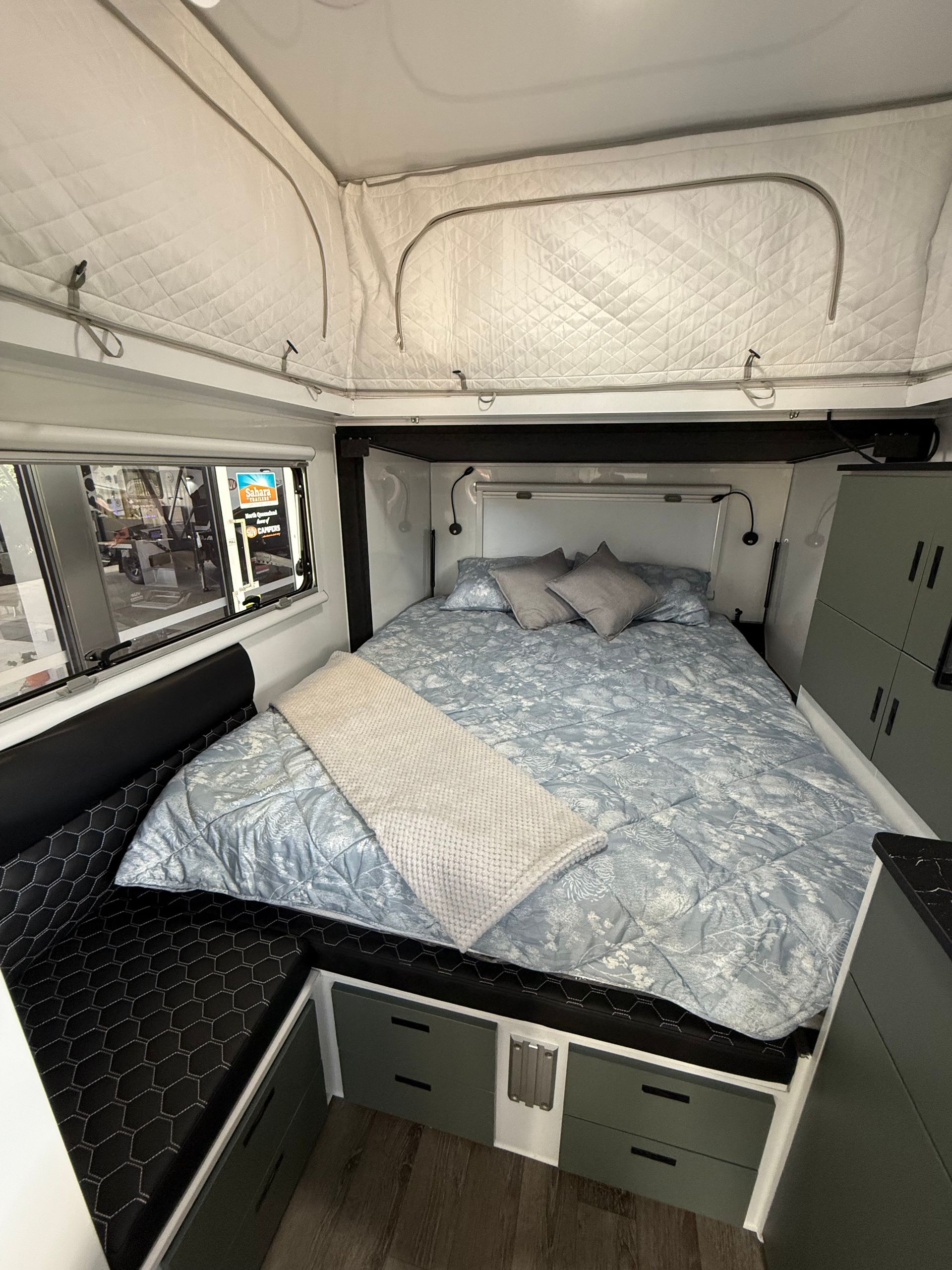 A bedroom in a camper with a bed and a window.