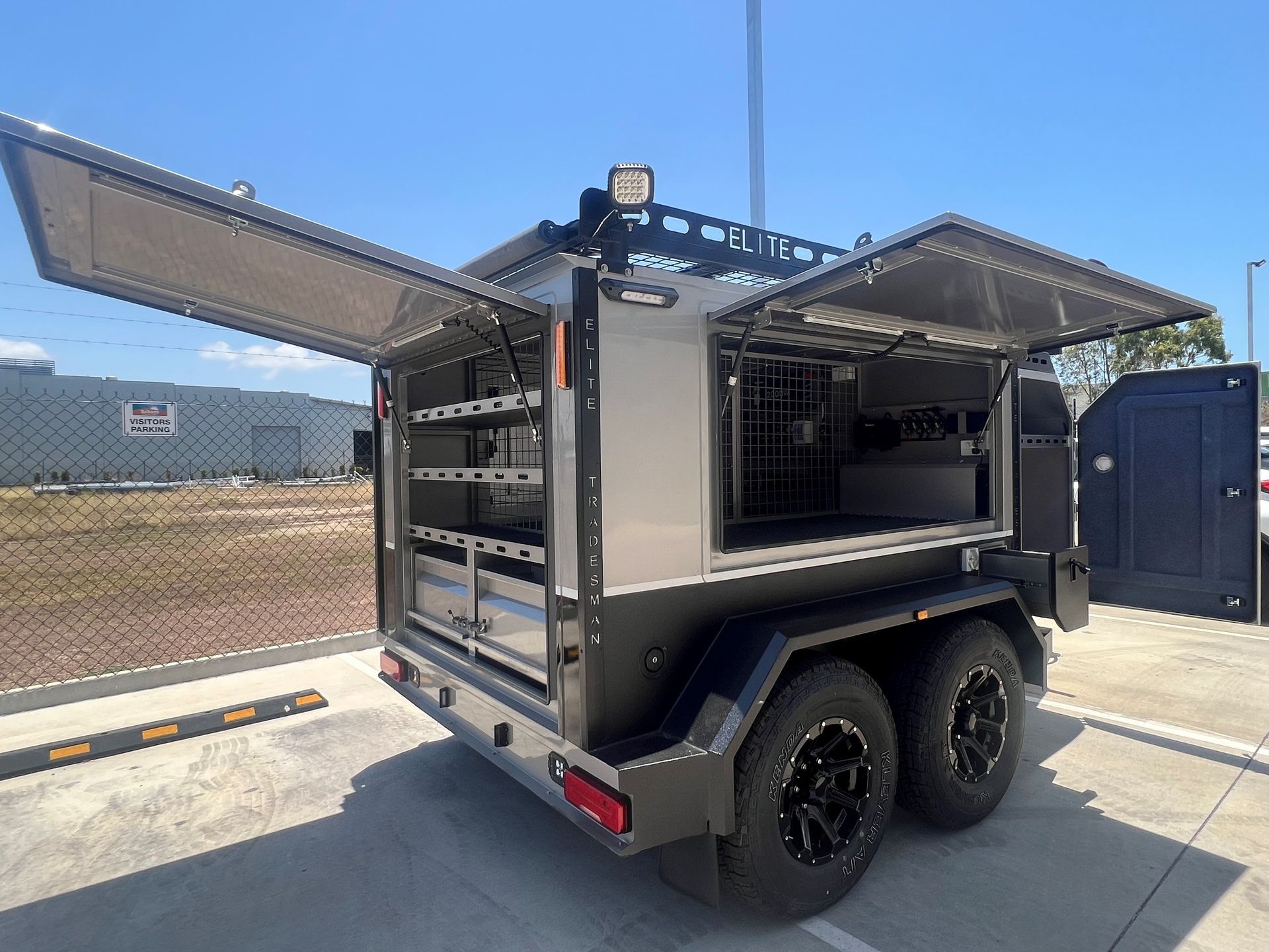 A trailer with its doors open is parked in a parking lot.