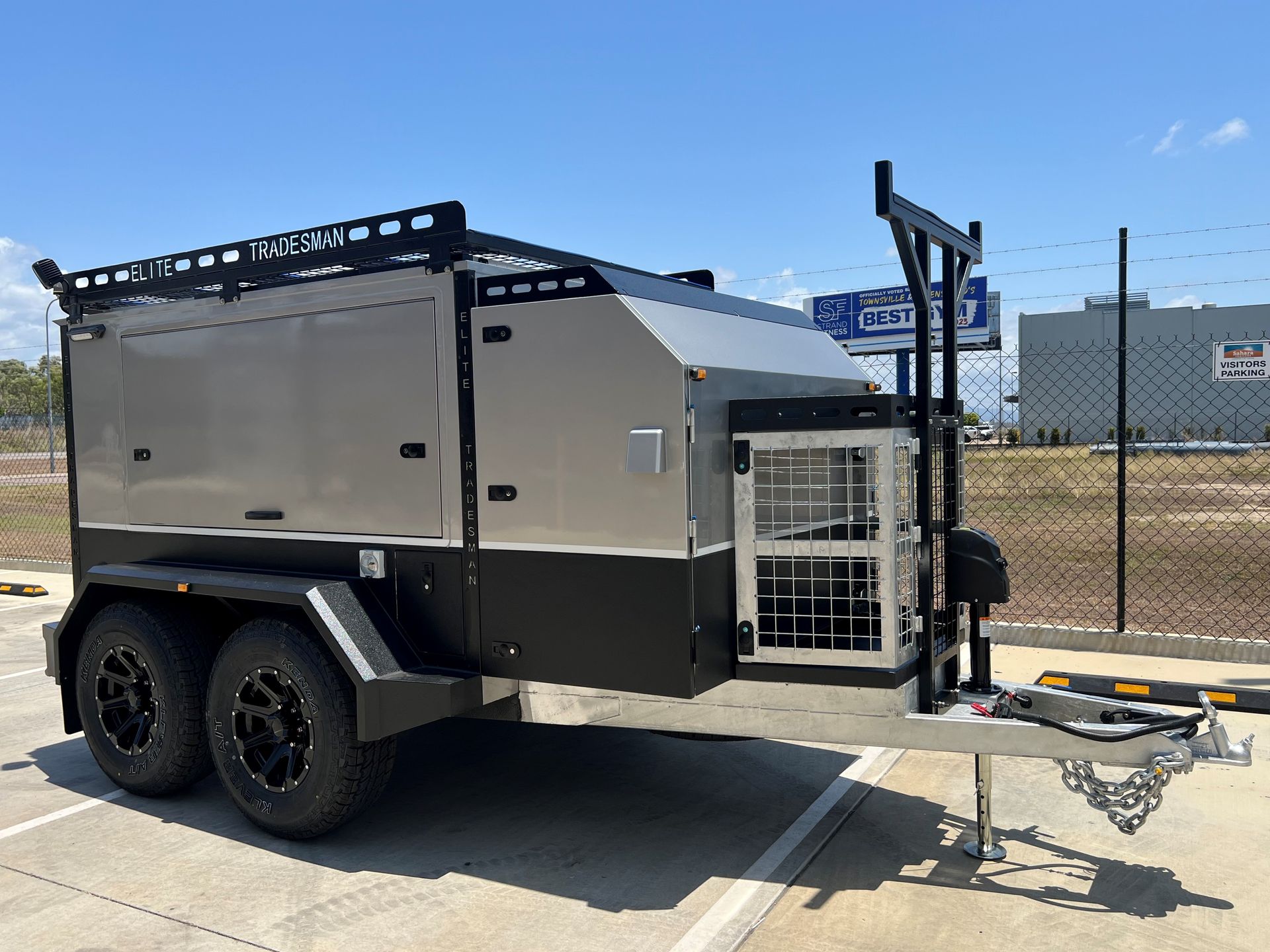 A trailer is parked in a parking lot next to a fence.