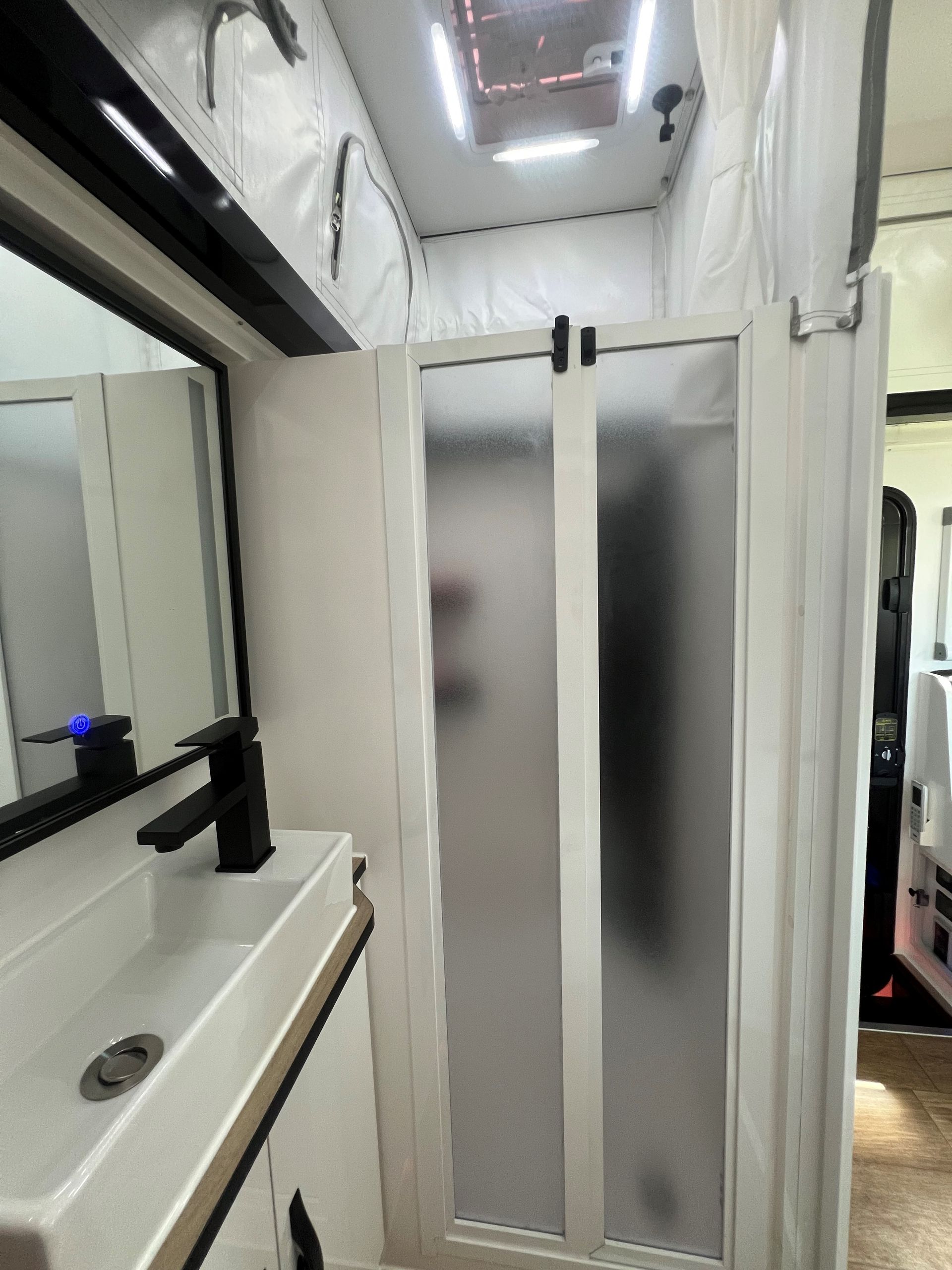 A bathroom with a sink , mirror and shower stall.