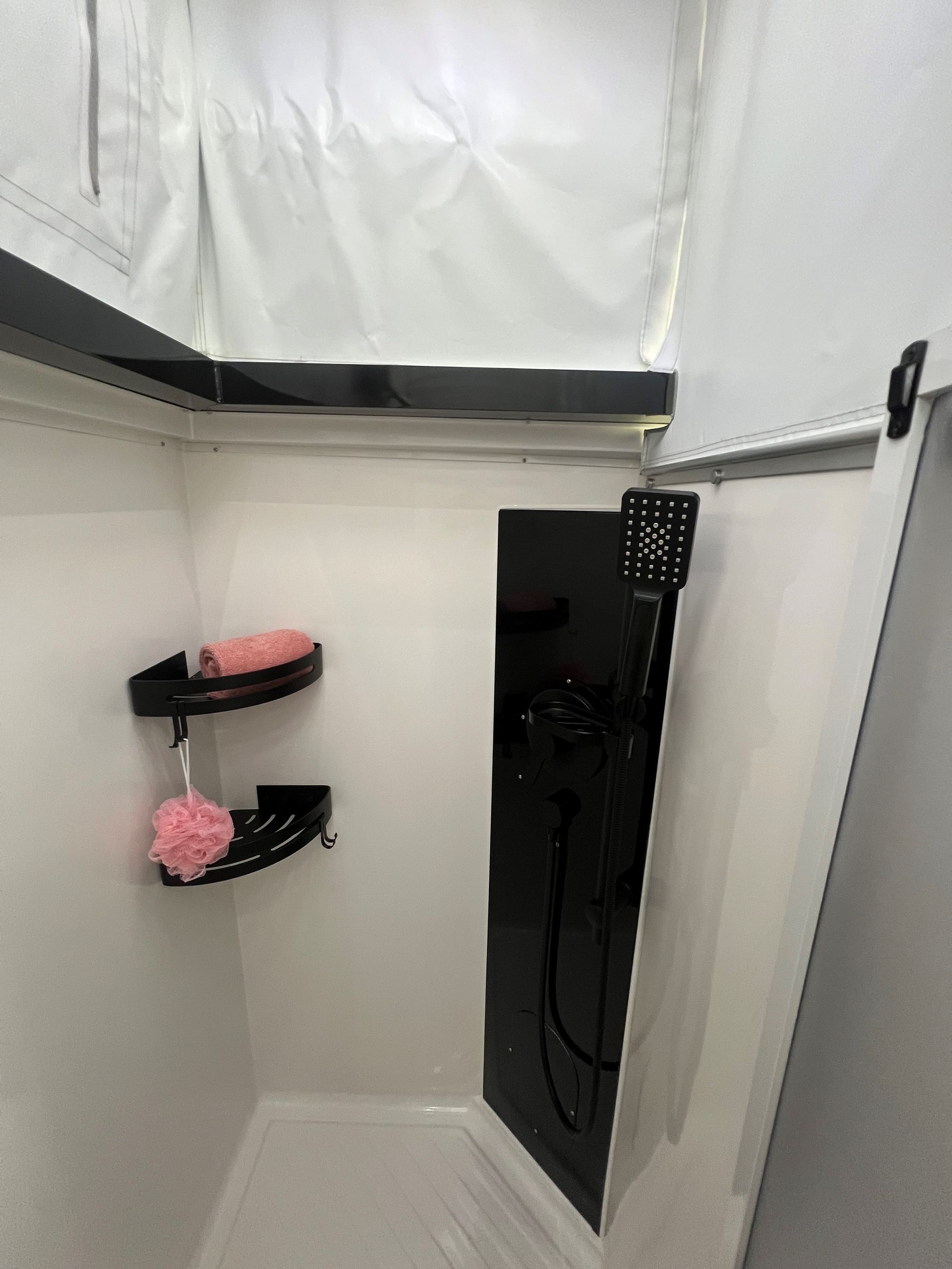 A bathroom with a shower and a black door.