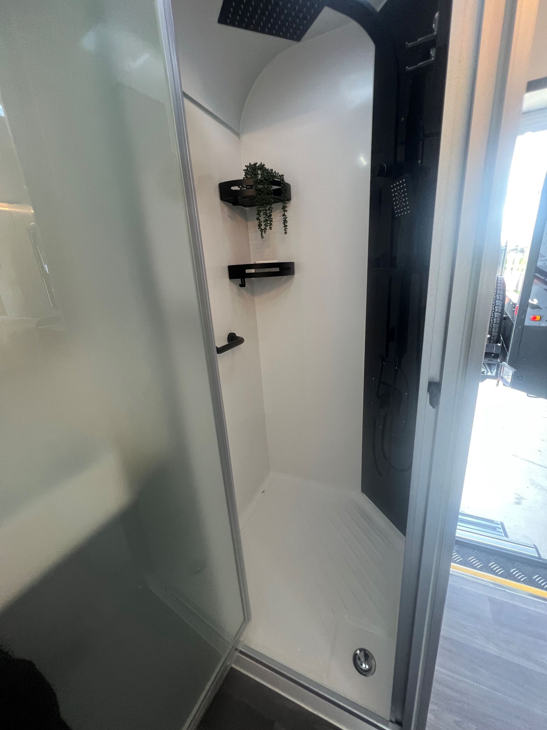 A bathroom with a walk in shower and a glass door.