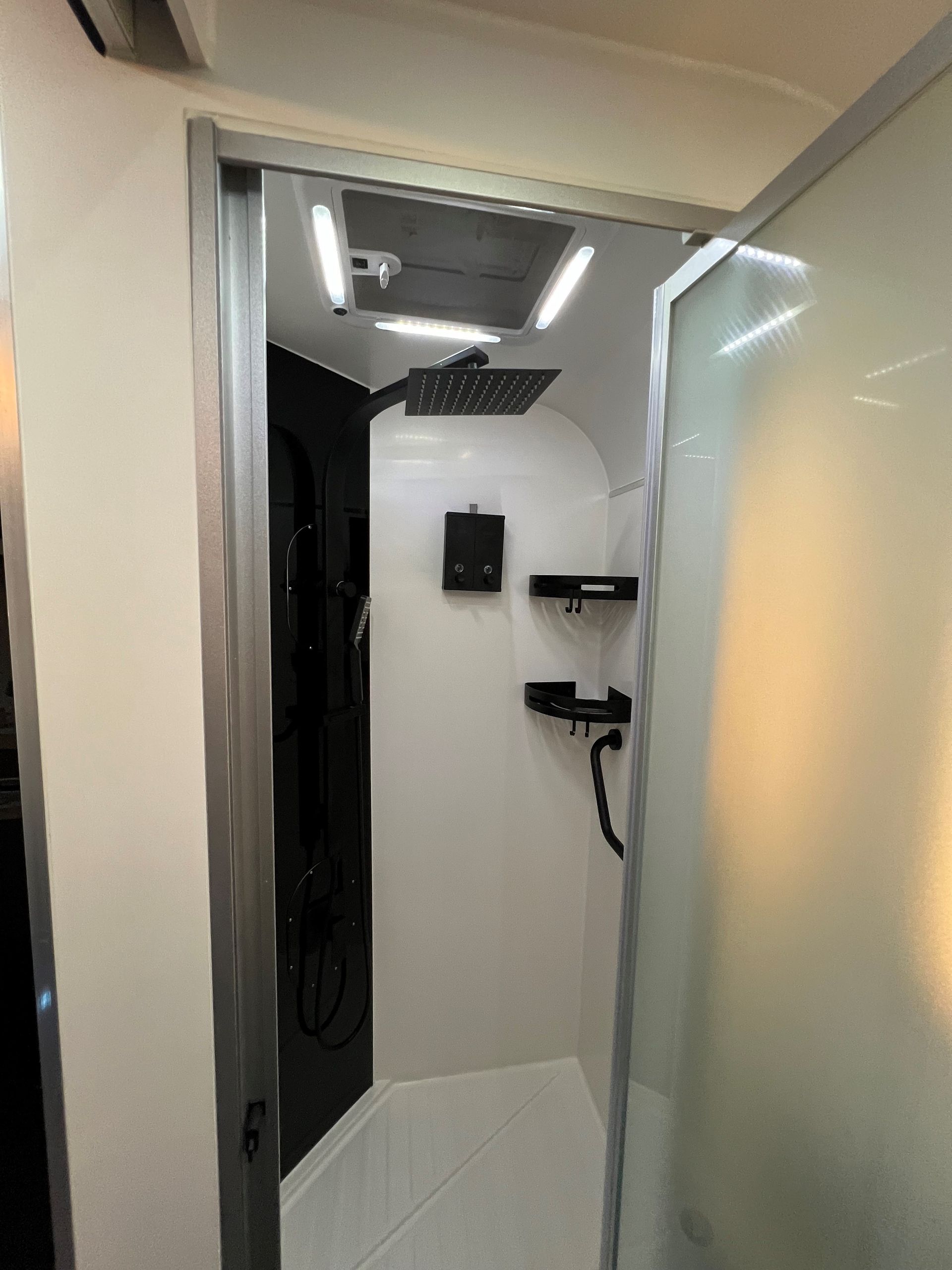 A bathroom with a shower and a door that is open.