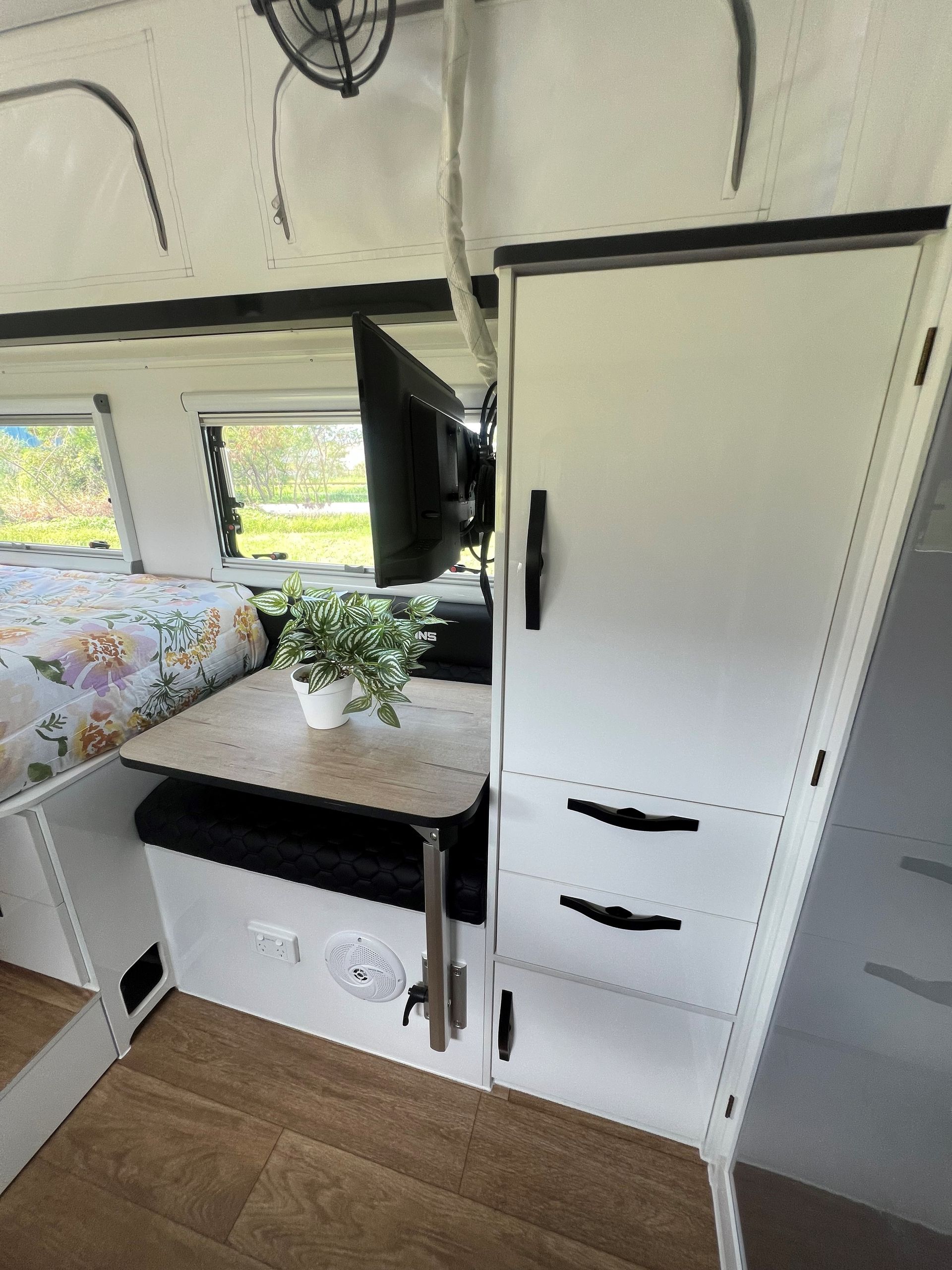 A camper with a table and a tv on the wall.