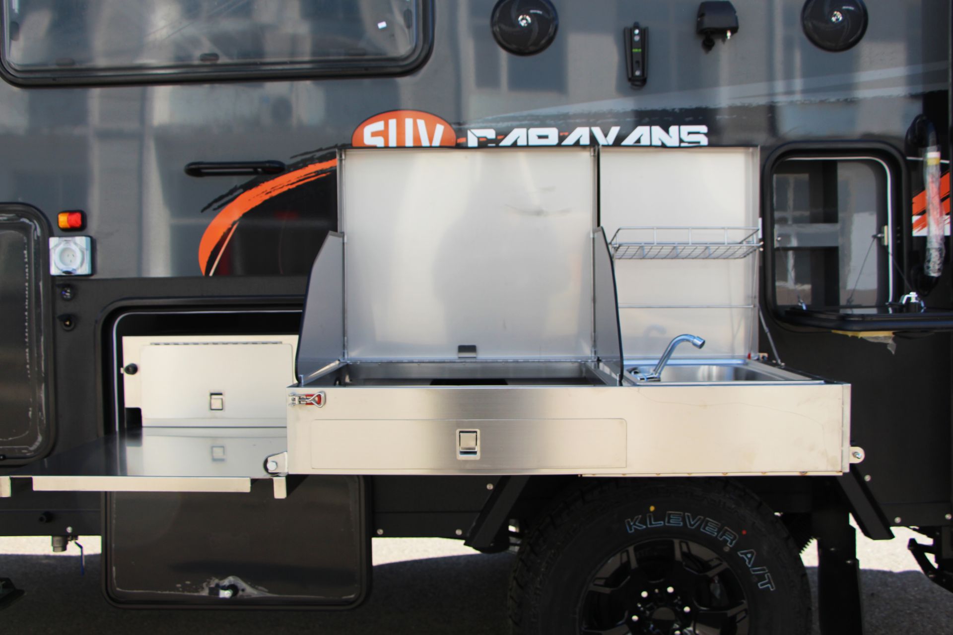 A black caravan with a stainless steel kitchen on the side.