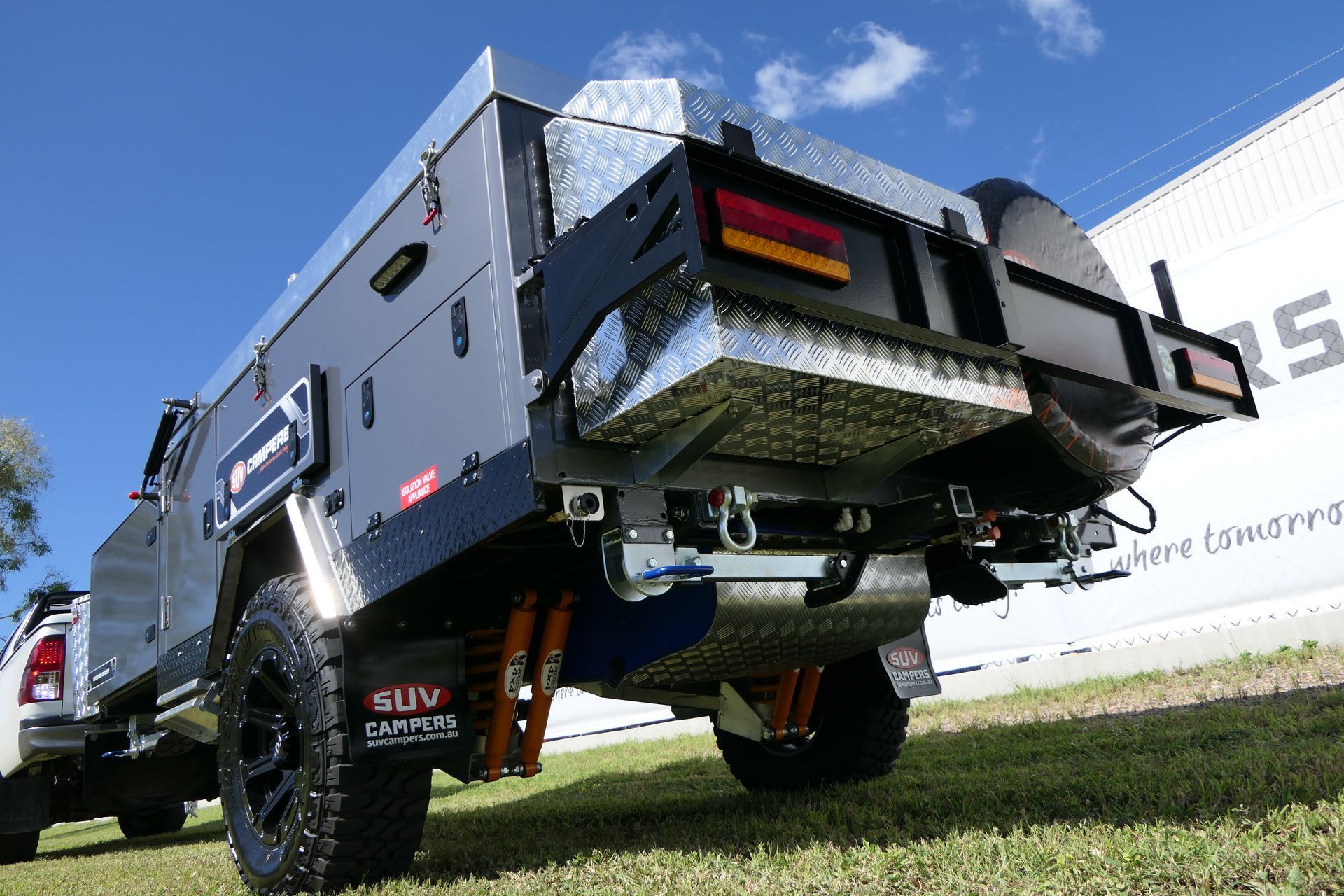 A truck with a trailer attached to it is parked in the grass.