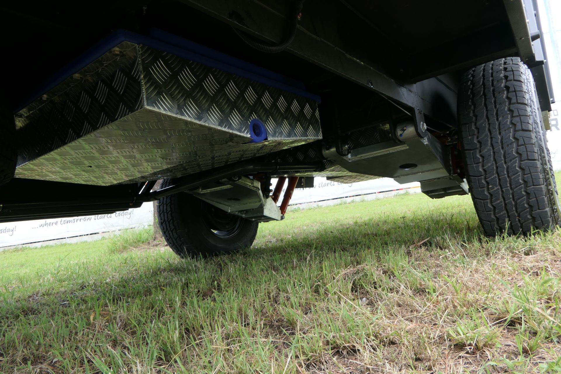 The underside of a truck with a fuel tank underneath it.