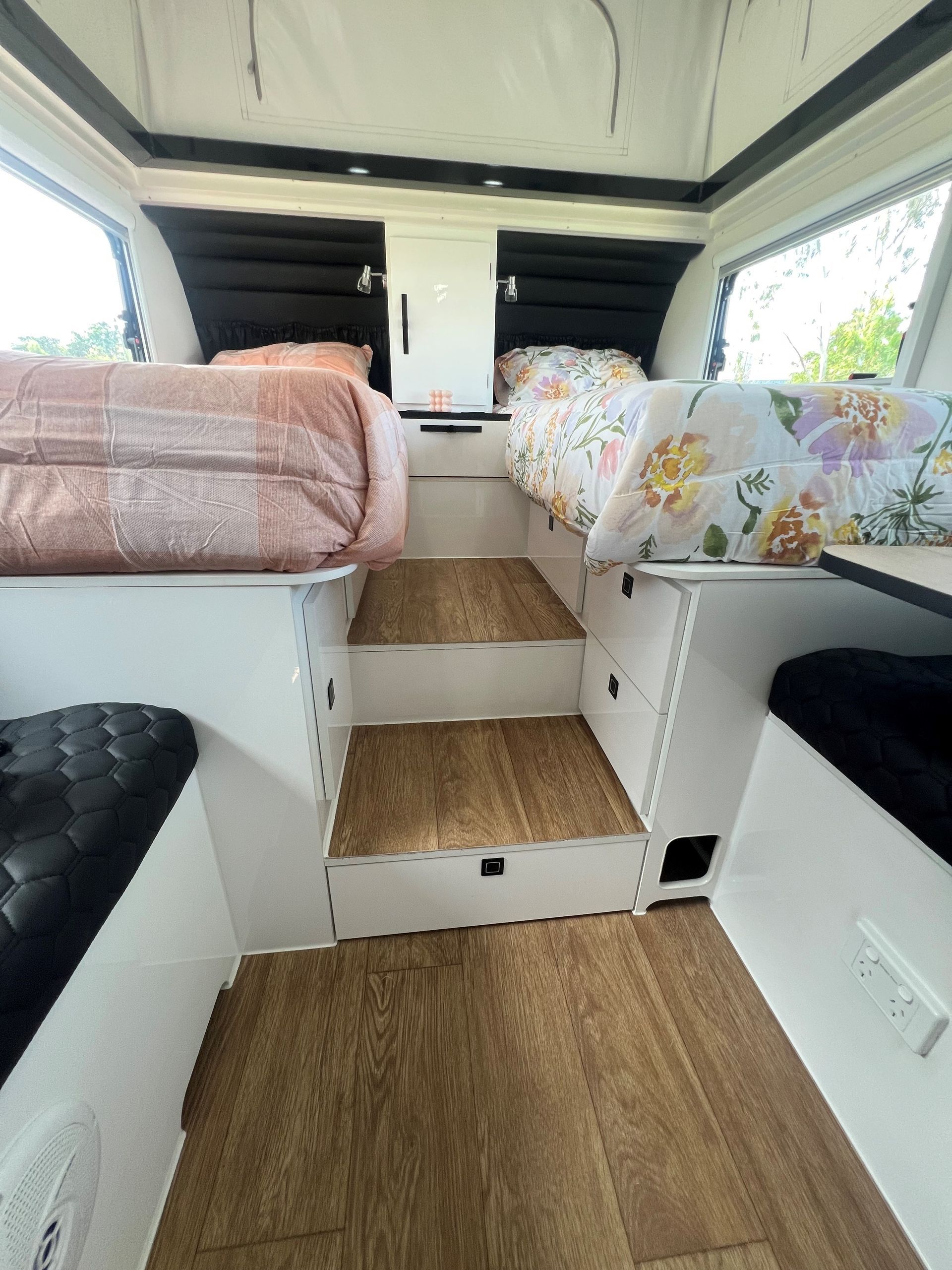 The inside of a camper van with a bed and stairs.