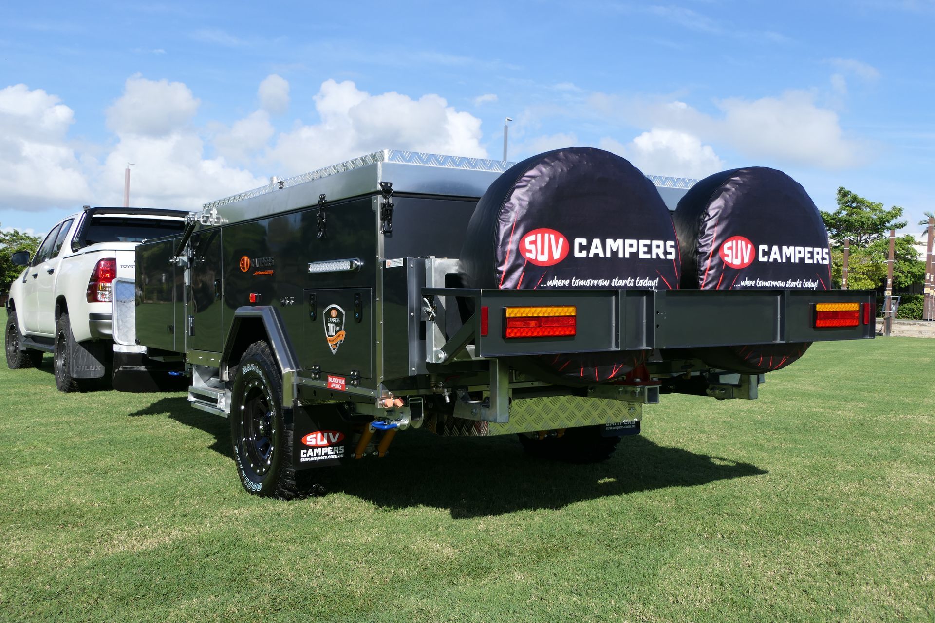A truck is towing a trailer in a grassy field.
