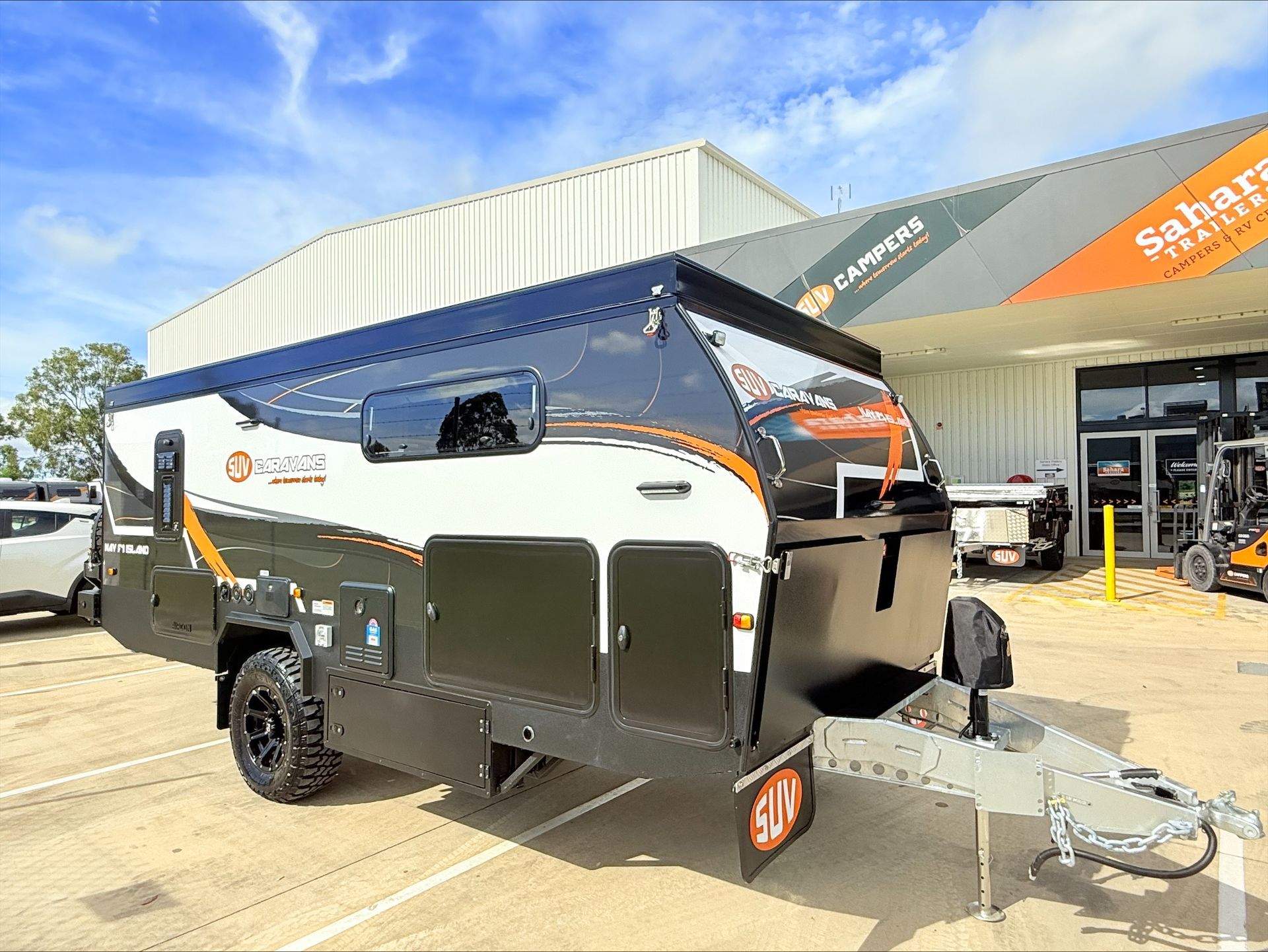 A black and white trailer is parked in front of a building.