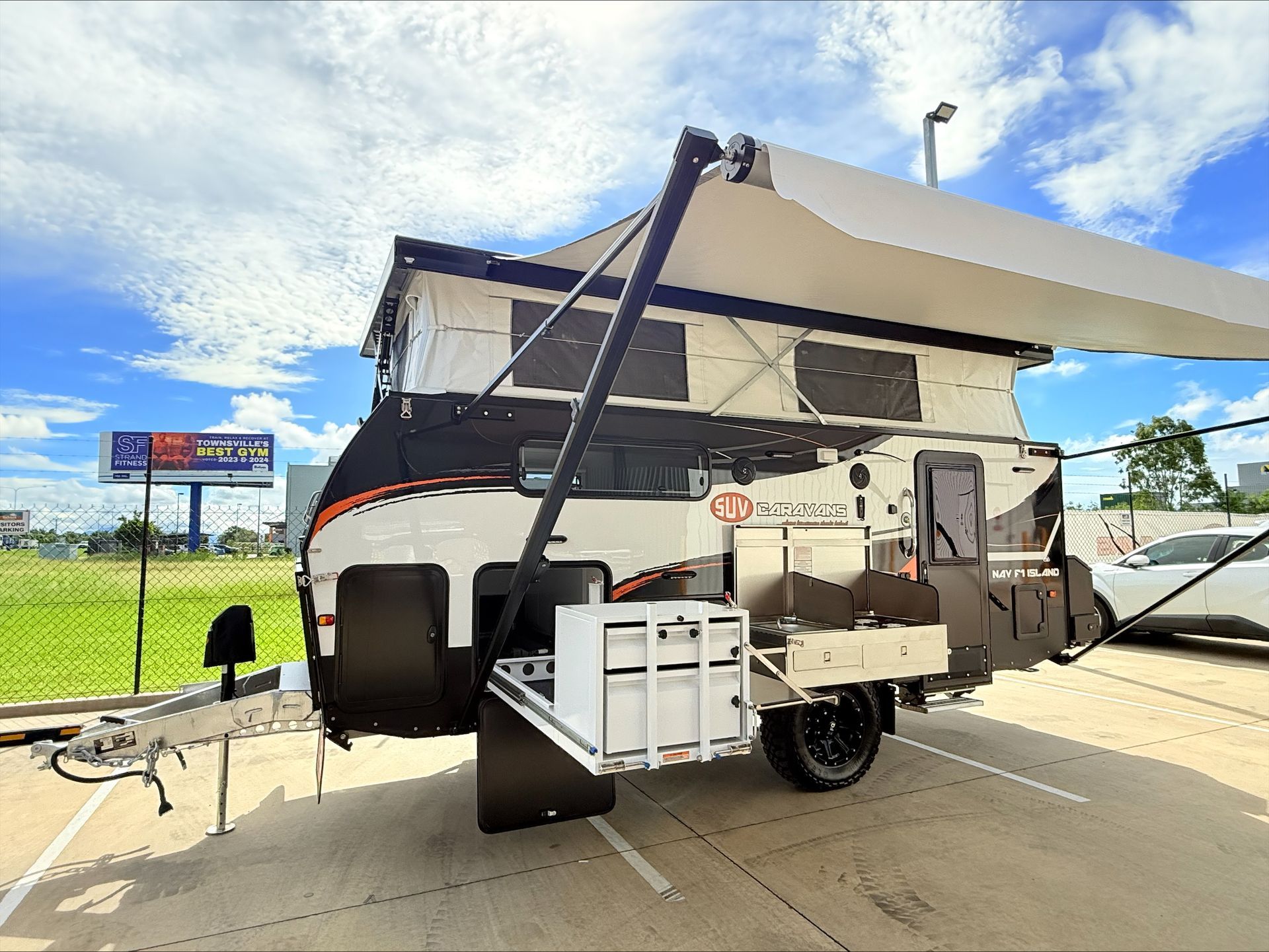 A trailer with a tent on top of it is parked in a parking lot.