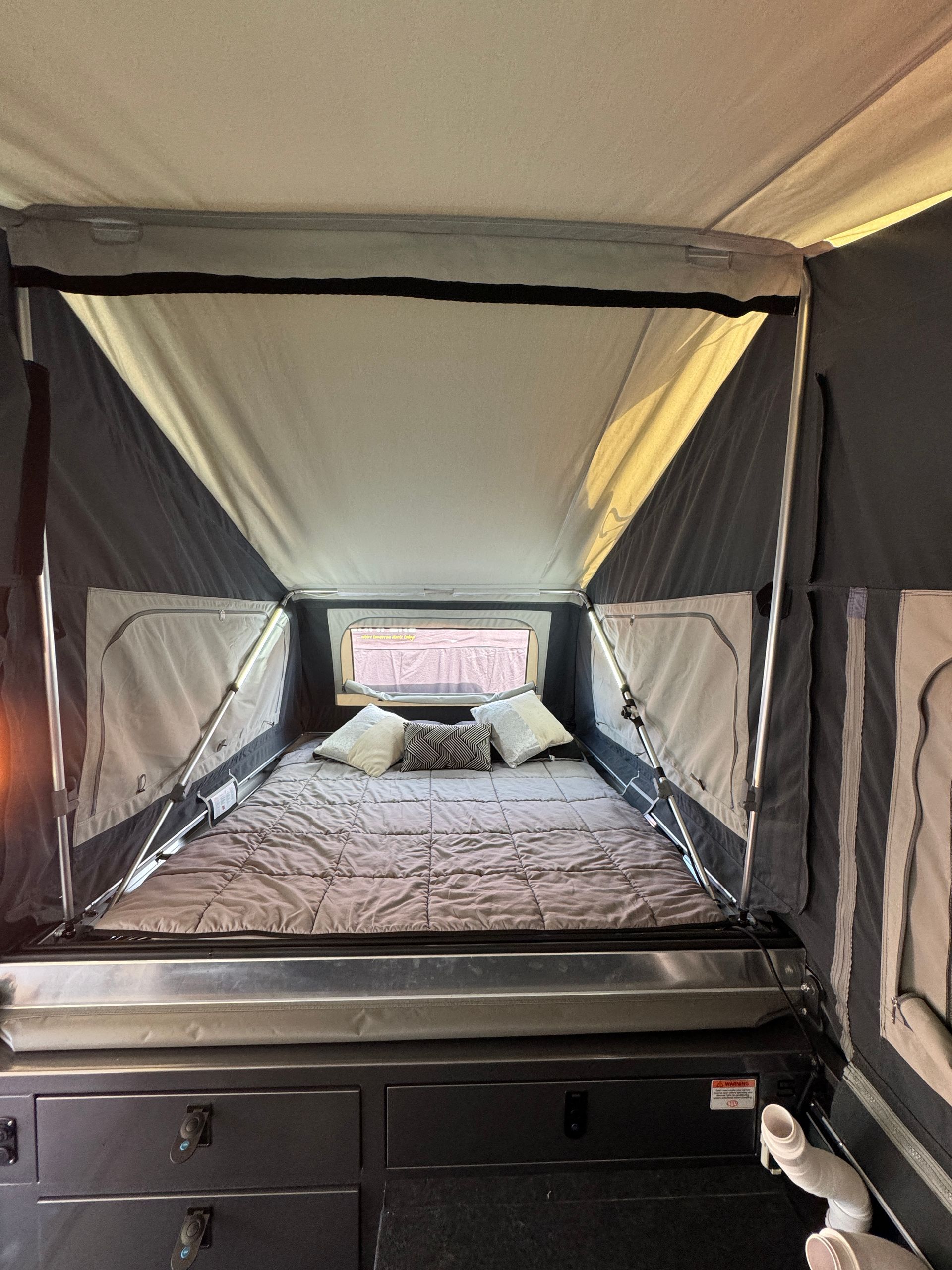 The inside of a camper with a bed and a window.