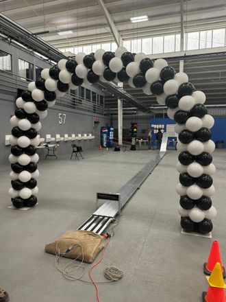 A large arch made of black and white balloons in a warehouse.