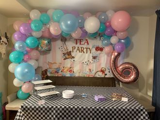 A room decorated for a tea party with balloons and a table.