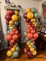 Two columns of balloons are sitting on a wooden floor in a room.