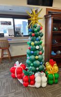 Two columns of balloons are sitting on a wooden floor in a room.