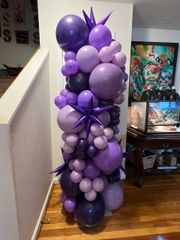 A bunch of purple balloons are stacked on top of each other in a room.