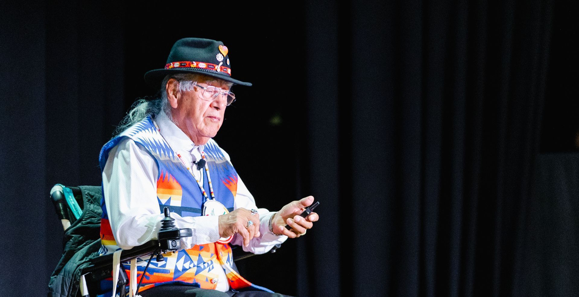 A man in a hat is sitting in a wheelchair on a stage.