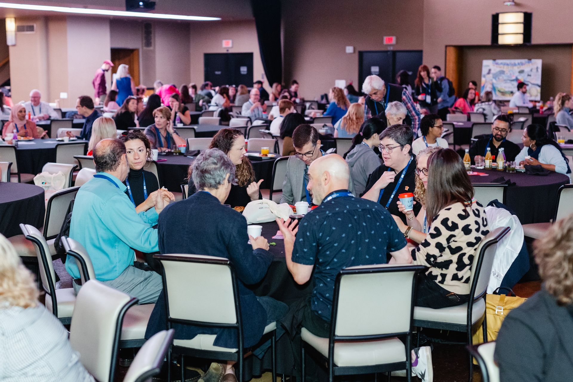 A large group of people are sitting at tables in a large room.
