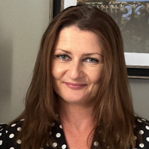 A woman with long hair and pink lipstick is wearing a black shirt.