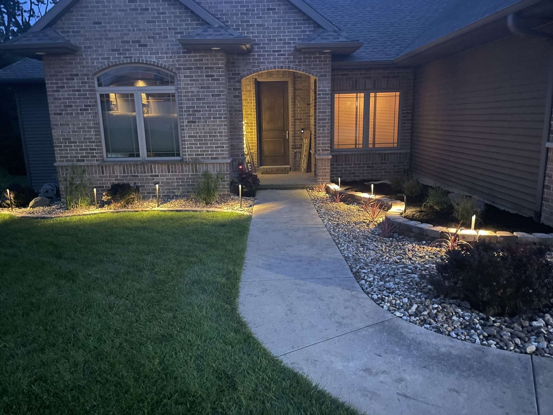 A brick house with a walkway leading to the front door at night