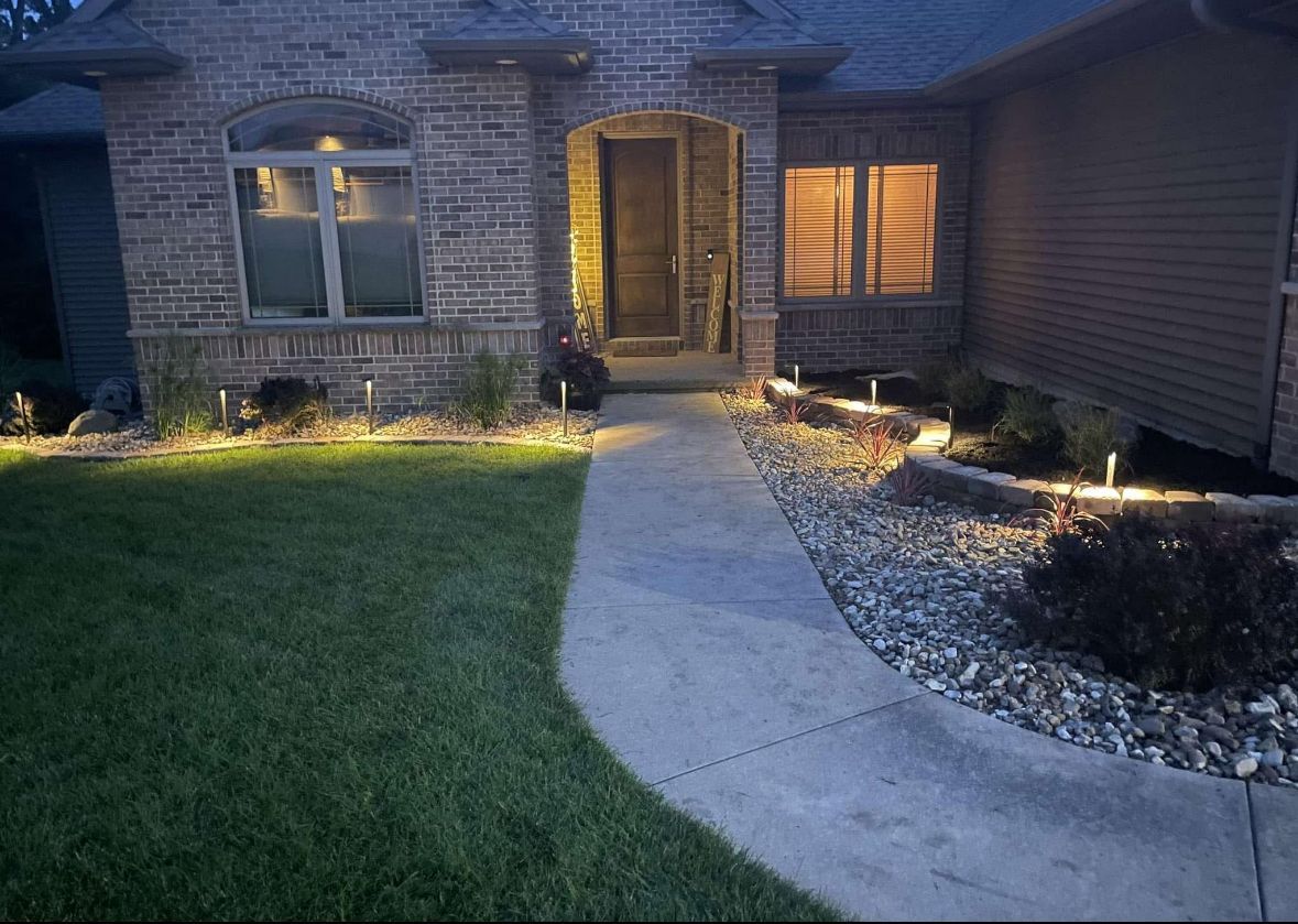 A house is lit up at night and has a large lawn in front of it