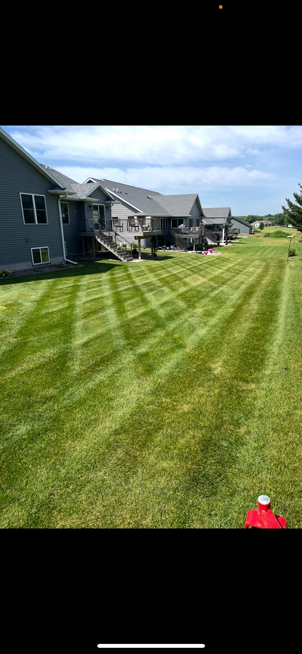 A lawn mower is cutting a lush green lawn.