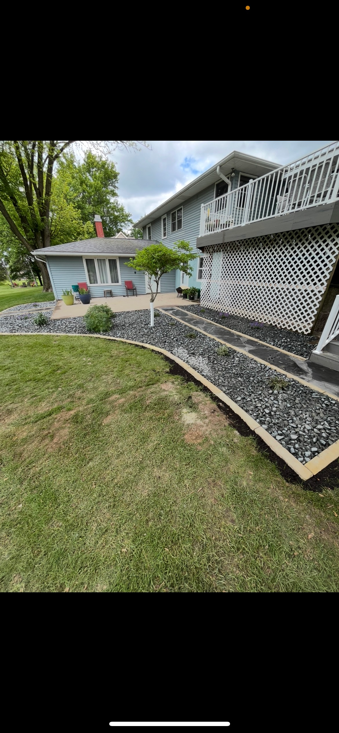 A bbq grill is sitting under a pergola in the backyard of a house.