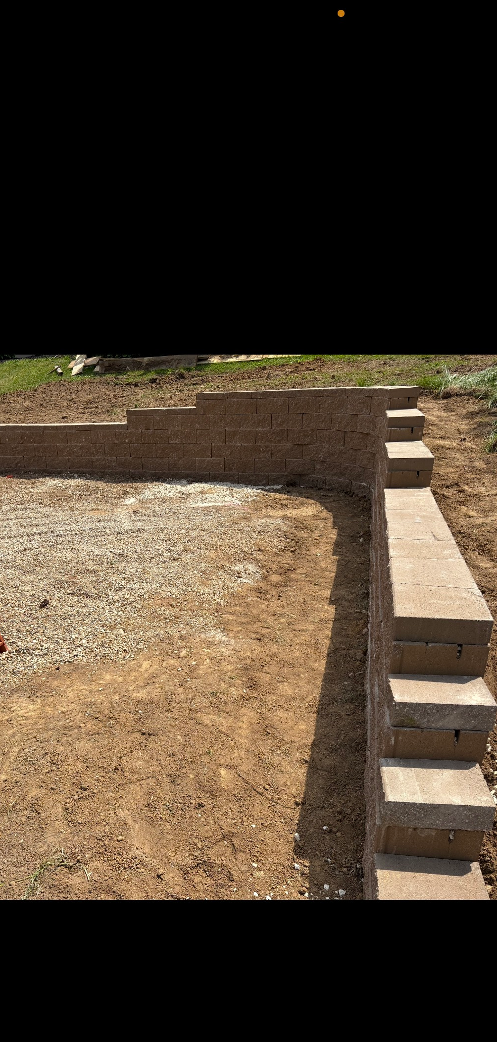 A stone wall with stairs leading up to it next to a house.