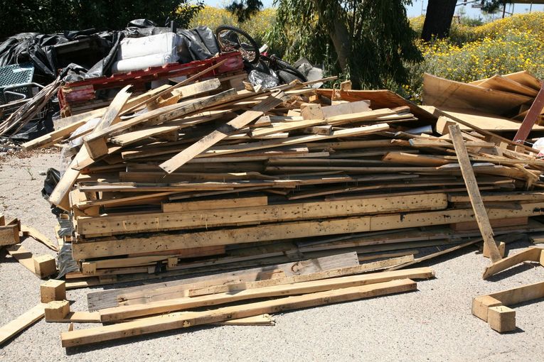 A pile of wood is sitting on a gravel road