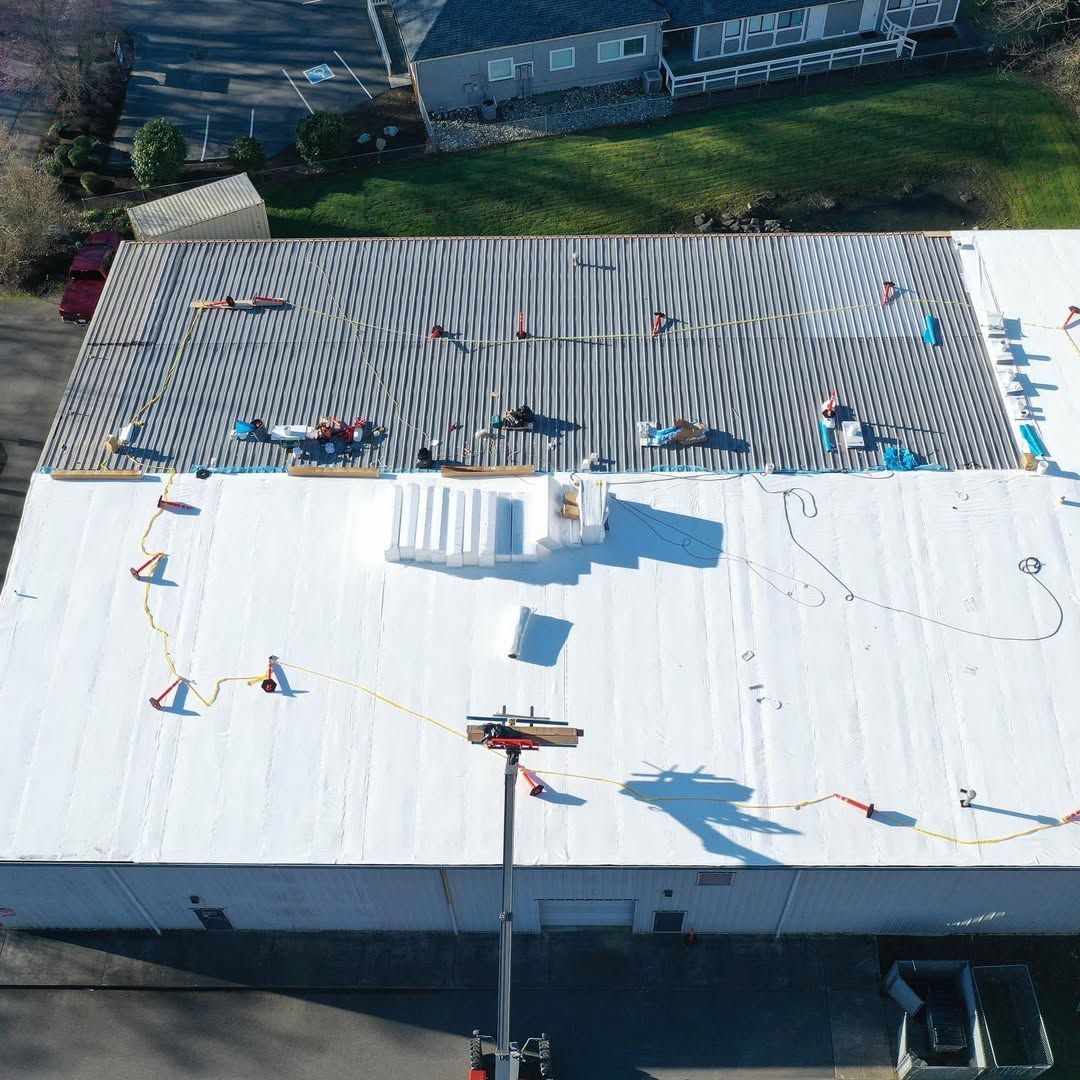 An aerial view of a building with a white roof being installed.