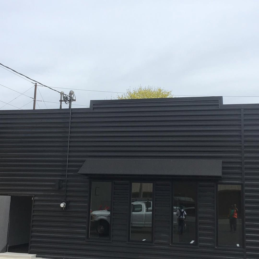 A black building with a white truck parked in front of it