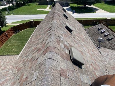 Steep shingled roof with vents and skylights, viewed from above beside a green lawn and street
