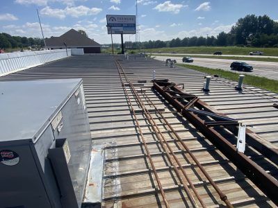 Rooftop construction with metal beams, HVAC unit, and road traffic in the distance
