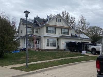 Suburban two-story house with beige siding, garage, and parked truck on a cloudy day