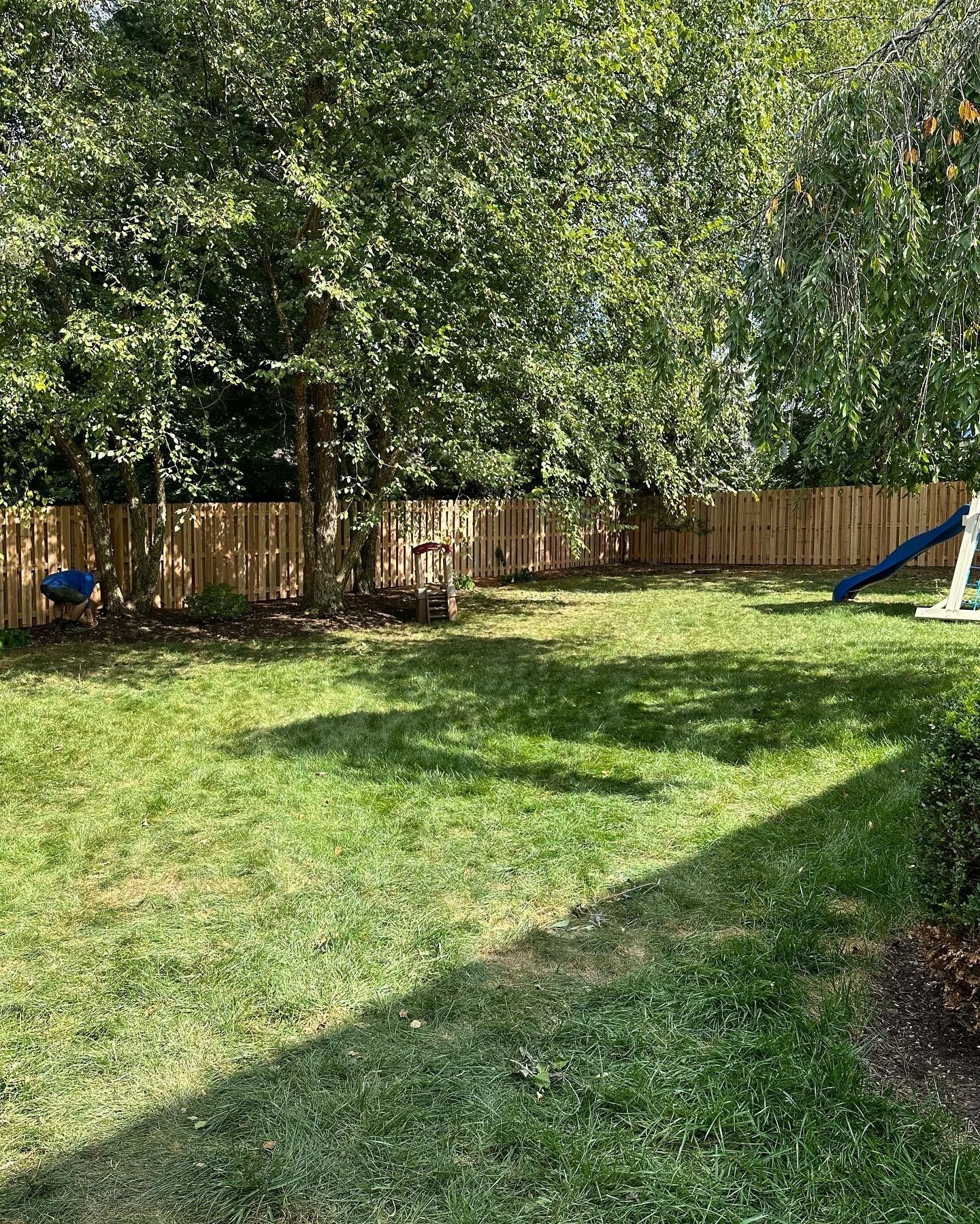 a backyard with a wooden fence and a swing set — Lexington, KY — Chafin Fence LLC