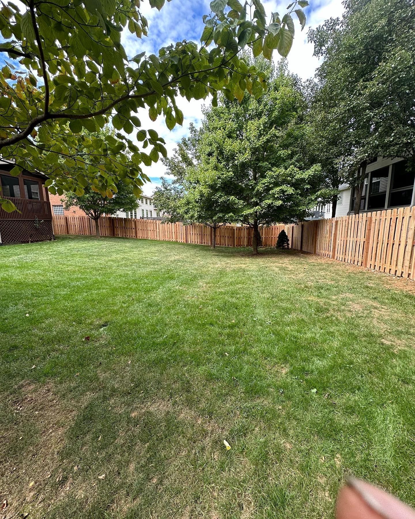 a person is holding a piece of grass in their hand in a backyard — Lexington, KY — Chafin Fence LLC