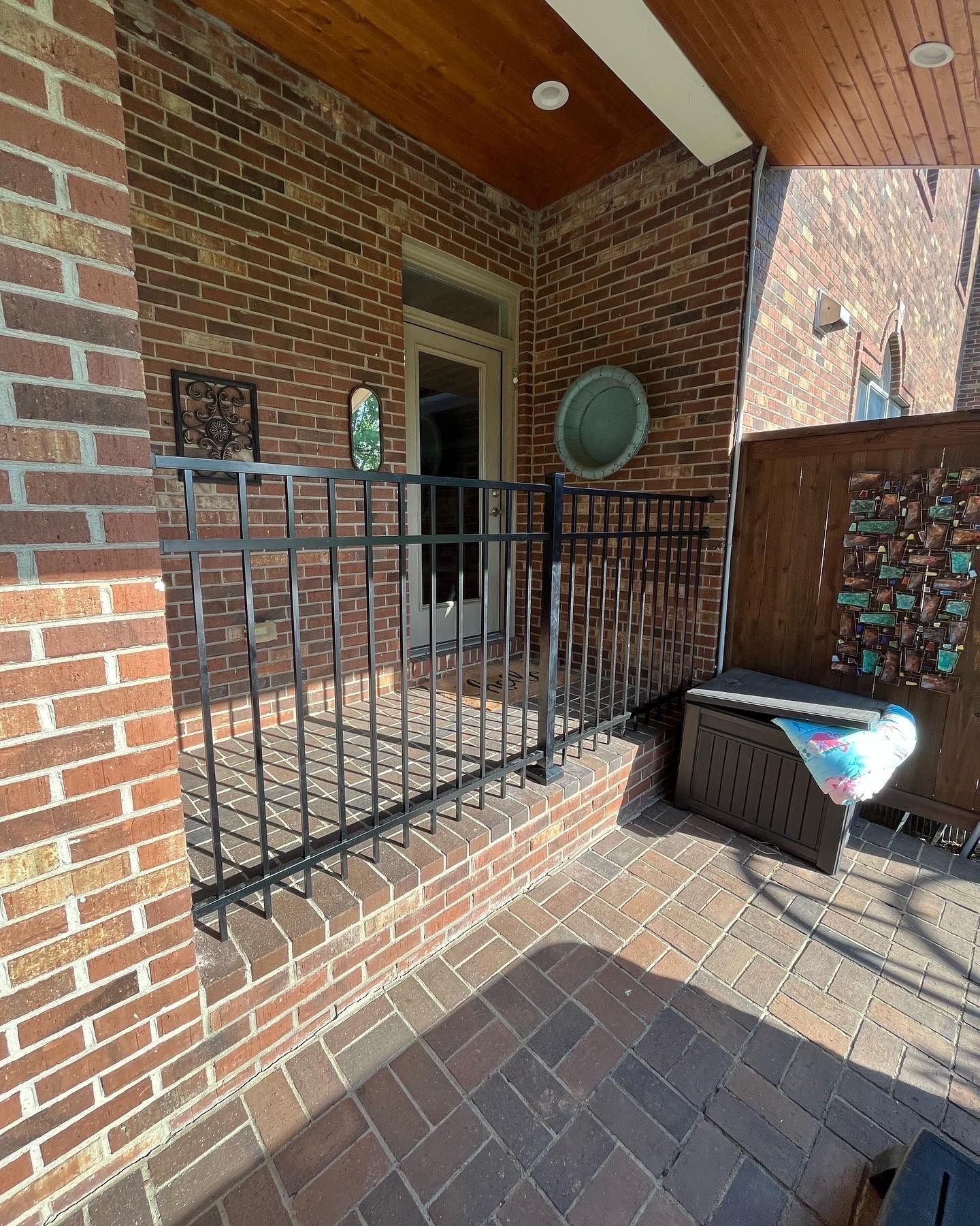 a brick porch with a metal railing and a bench — Lexington, KY — Chafin Fence LLC