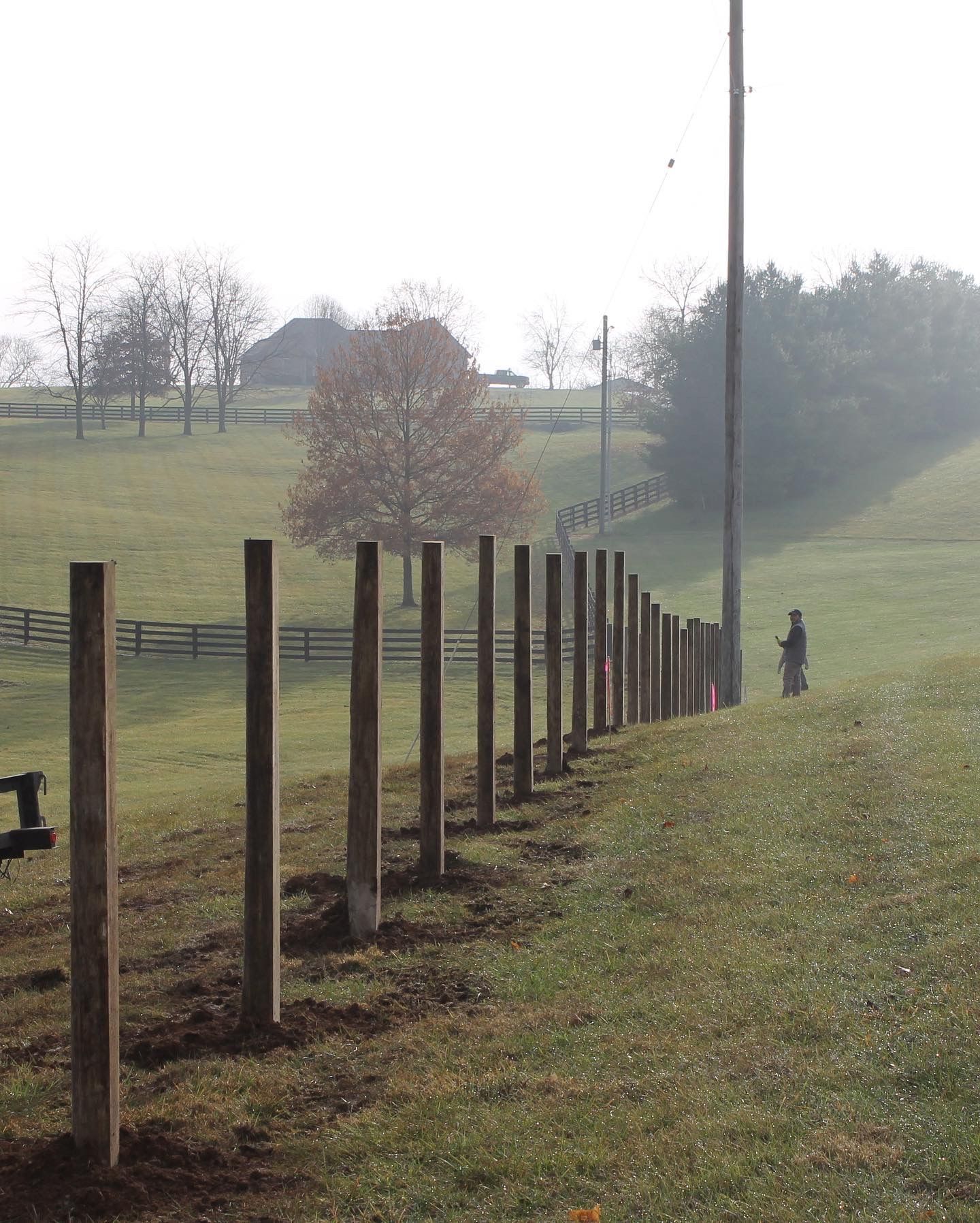 a row of wooden posts in a grassy field — Lexington, KY — Chafin Fence LLC