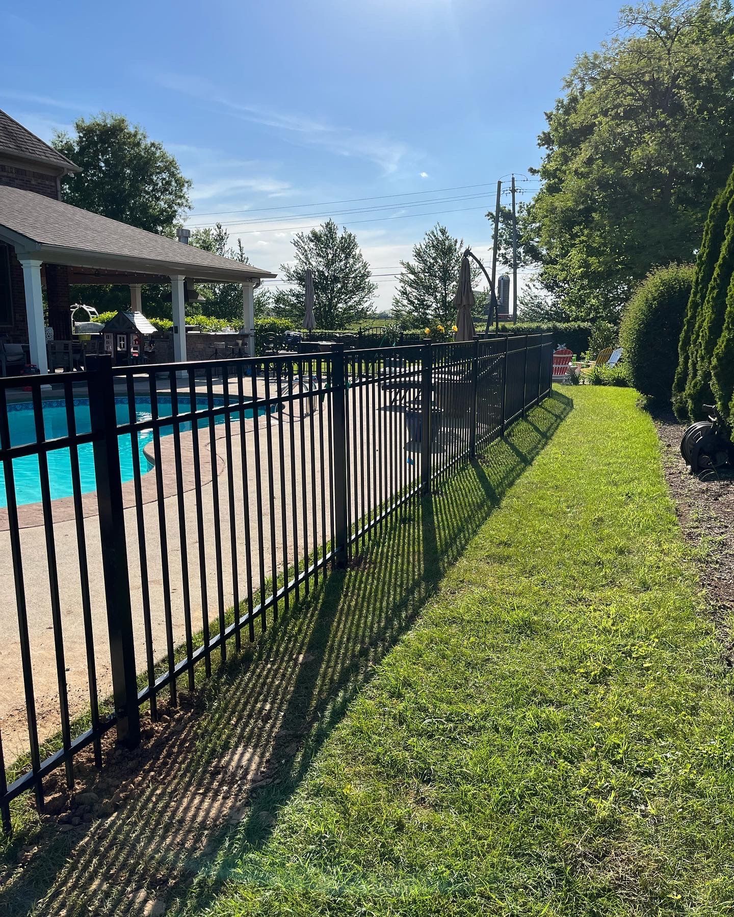 a black fence surrounds a swimming pool in a backyard — Lexington, KY — Chafin Fence LLC