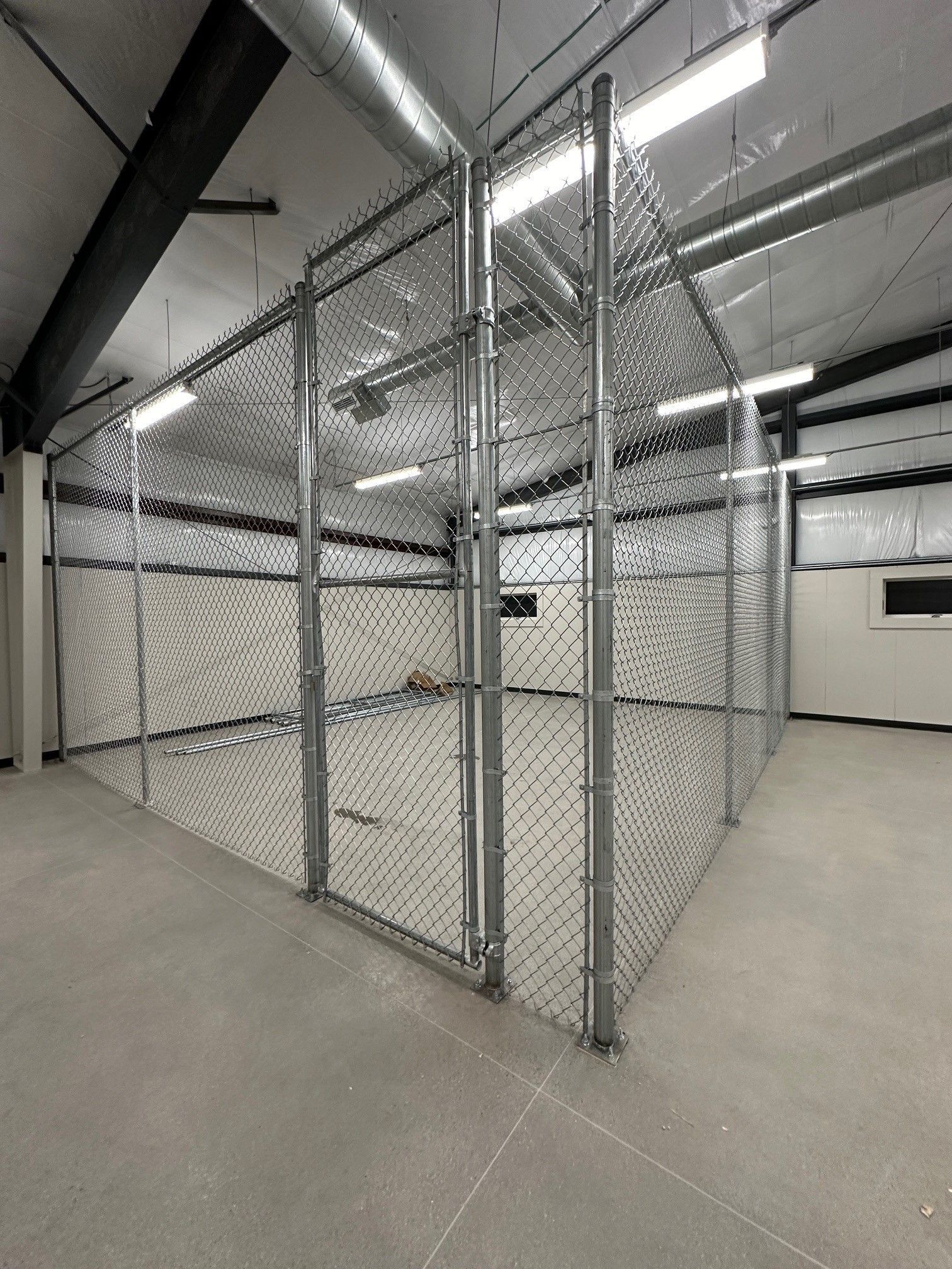 A large empty room with a chain link fence around it.