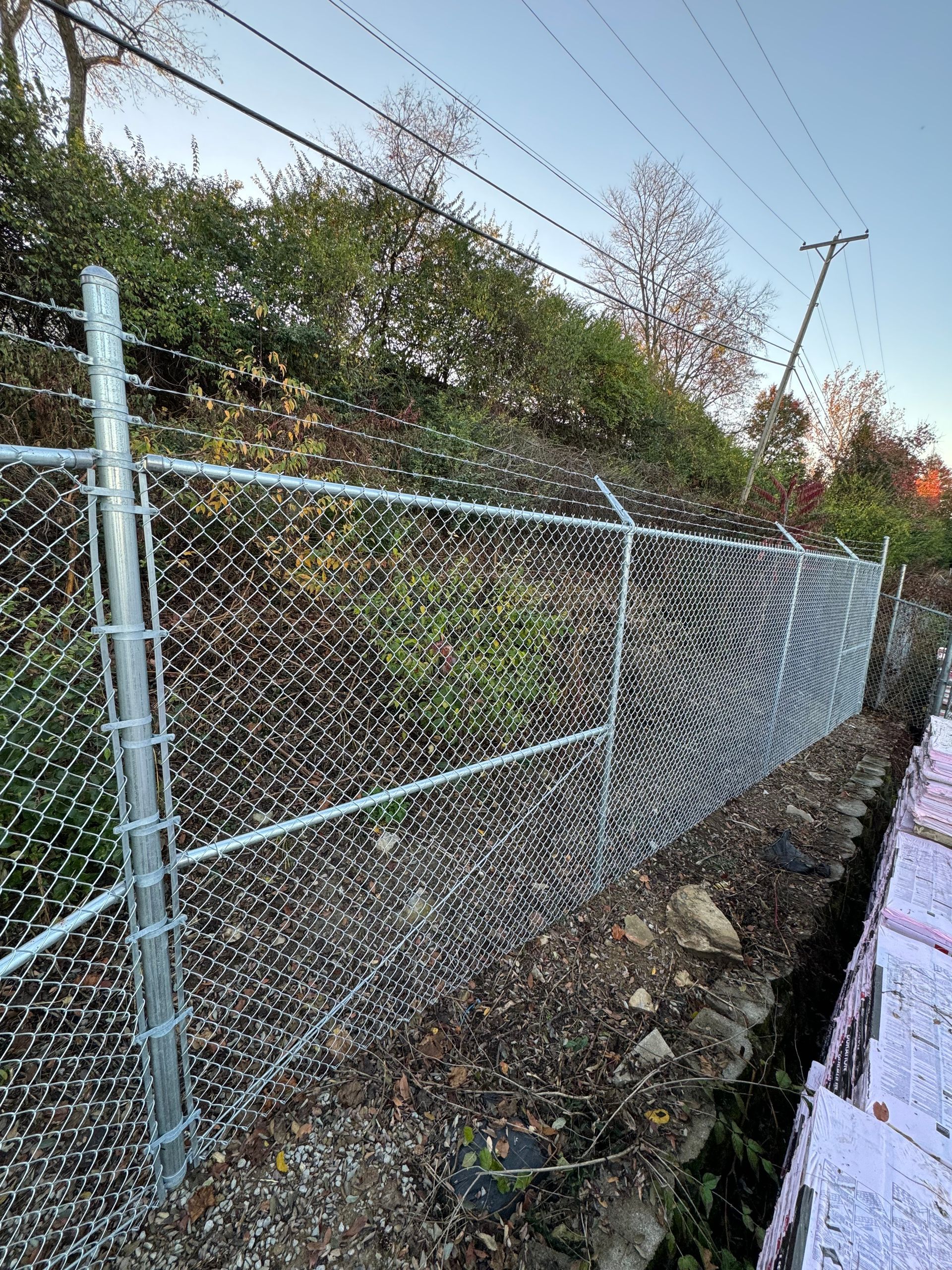 a chain link fence is sitting on top of a gravel hill — Lexington, KY — Chafin Fence LLC