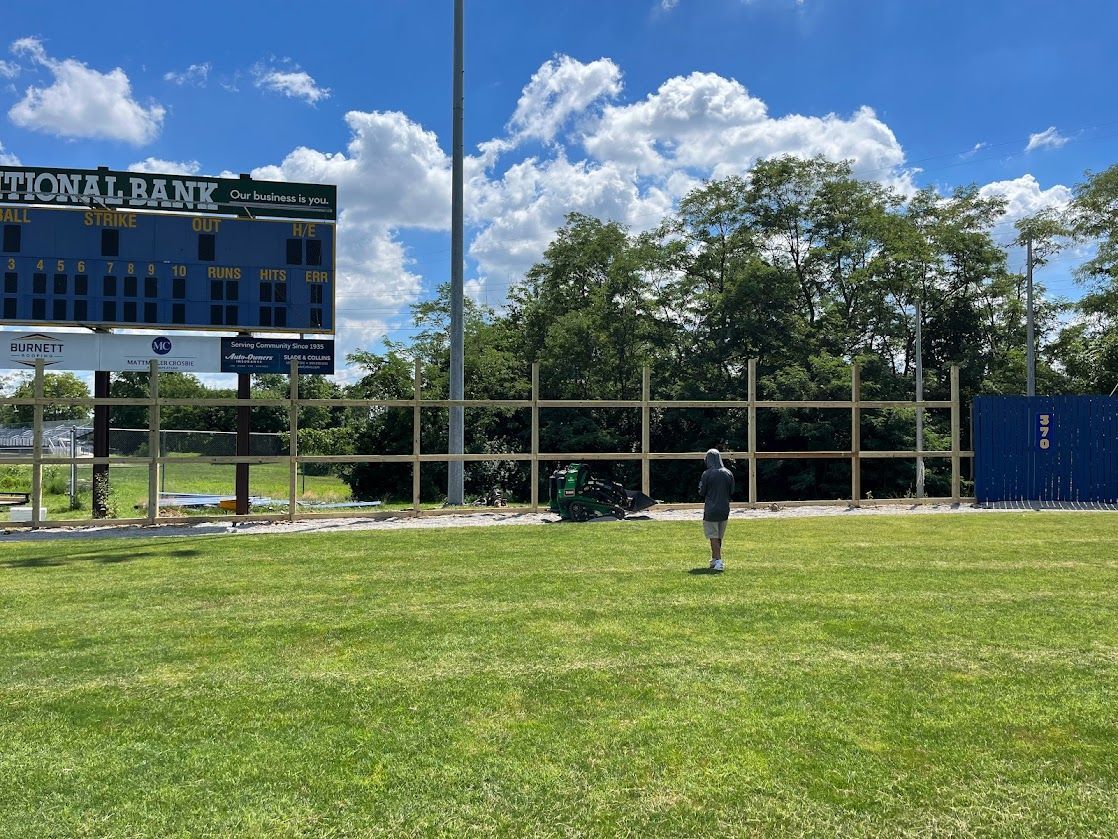a man is standing in a field with a scoreboard in the background — Lexington, KY — Chafin Fence LLC