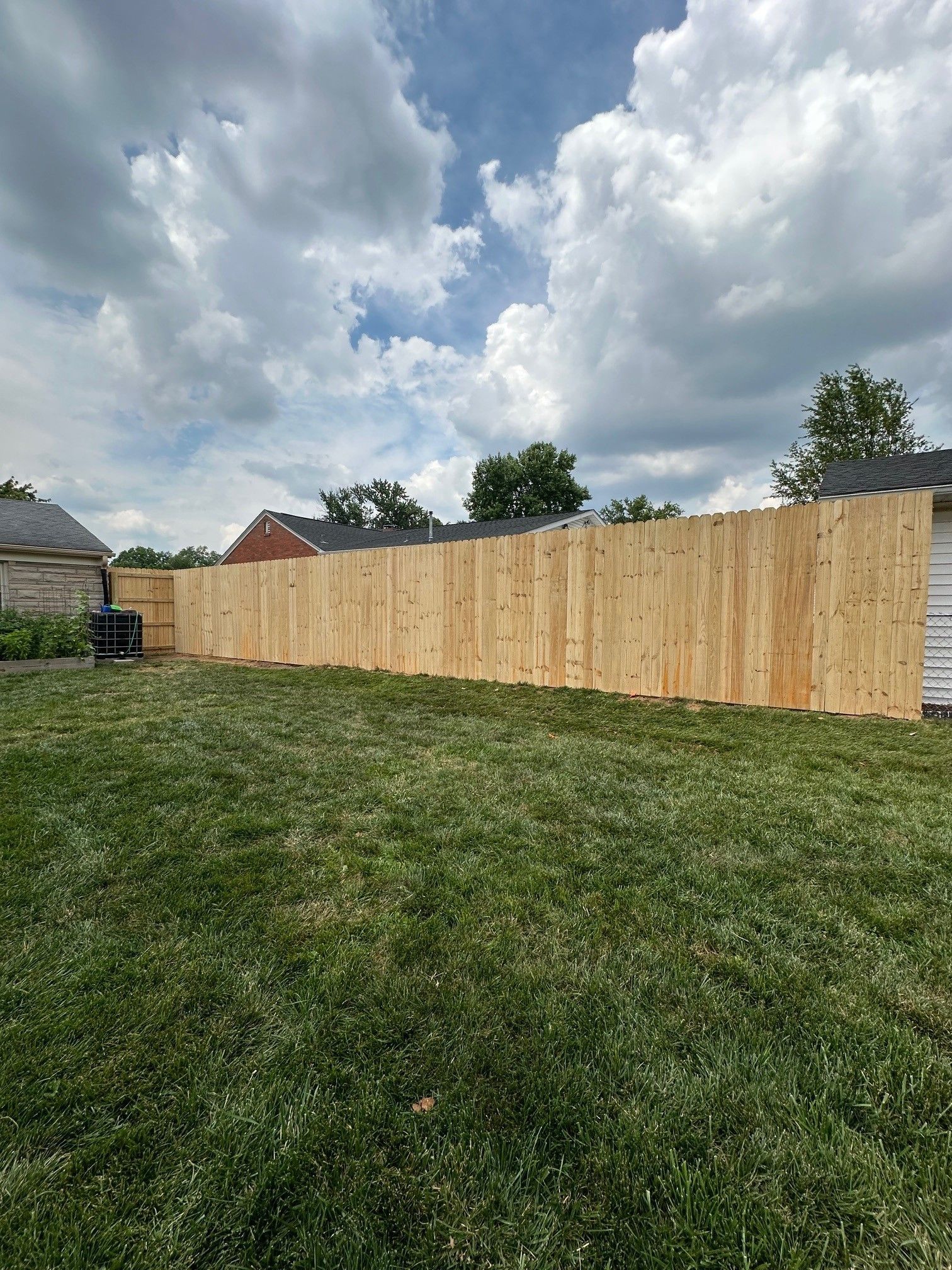 A wooden fence is sitting in the middle of a lush green field — Lexington, KY — Chafin Fence LLC