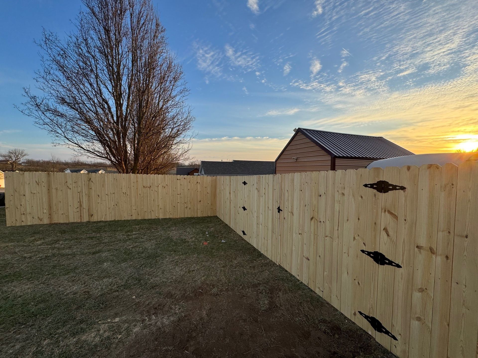 A wooden fence in a backyard with a sunset in the background — Lexington, KY — Chafin Fence LLC