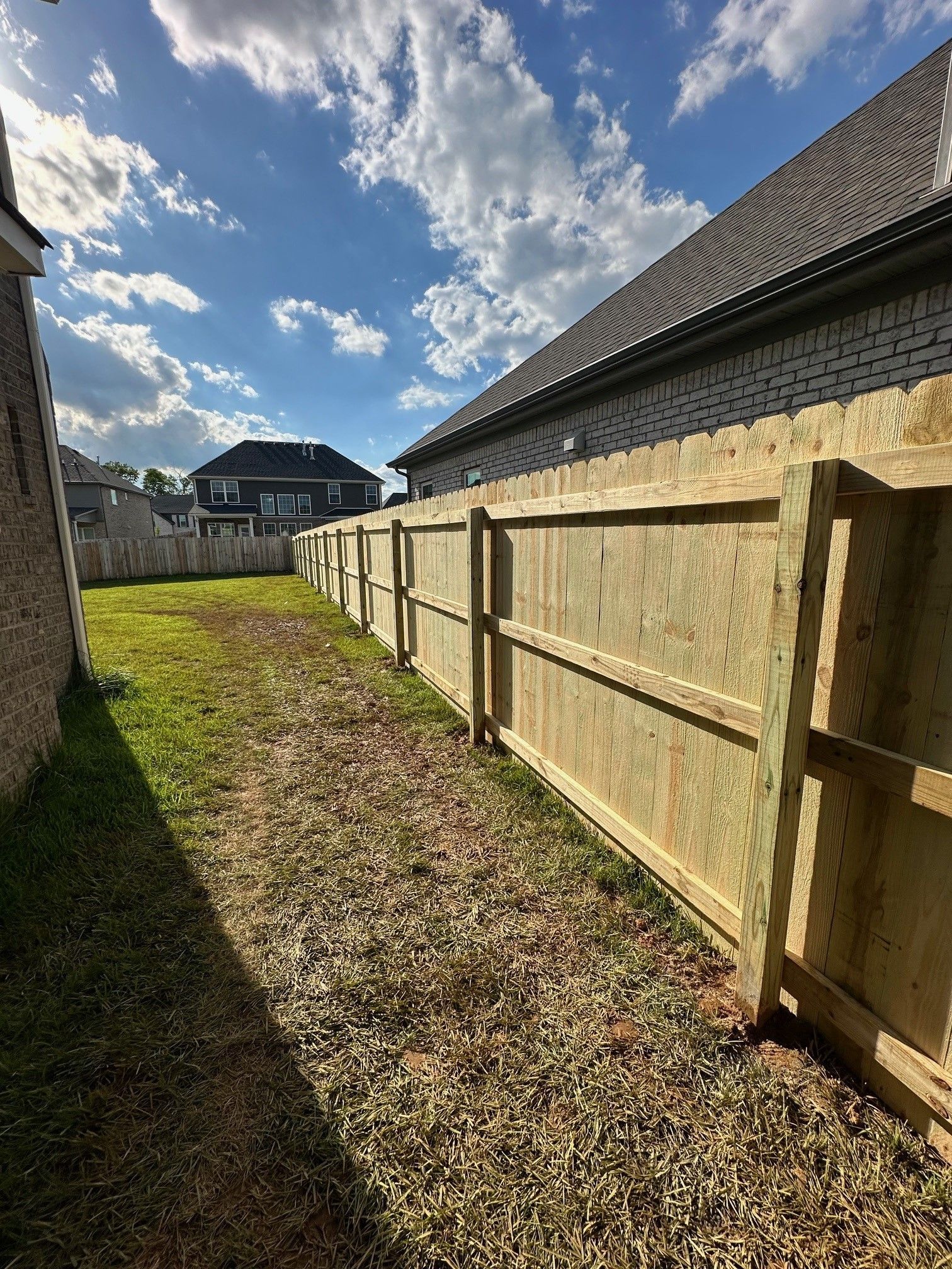 A wooden fence is in the backyard of a house.