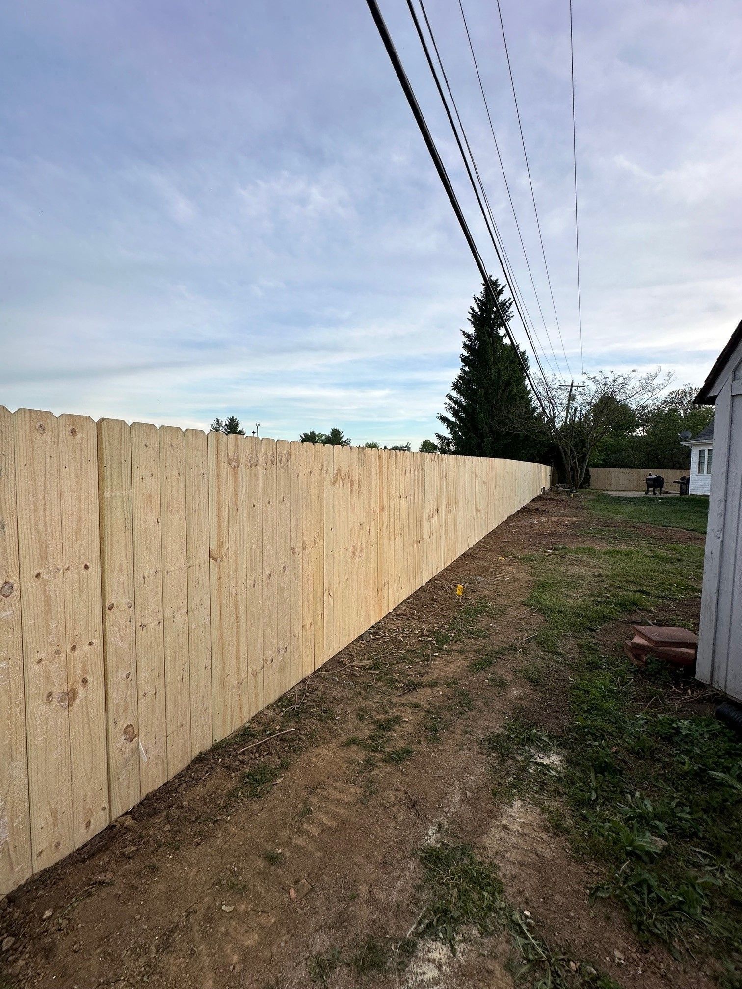 A wooden fence is being built in the backyard of a house.